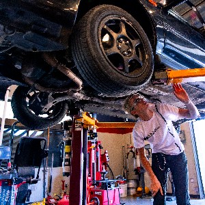 A student inspects the underside of a car.